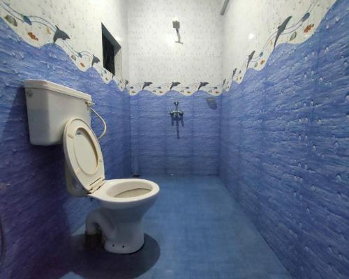 a blue tiled bathroom with a toilet in it at Luciano Guest House in Arambol