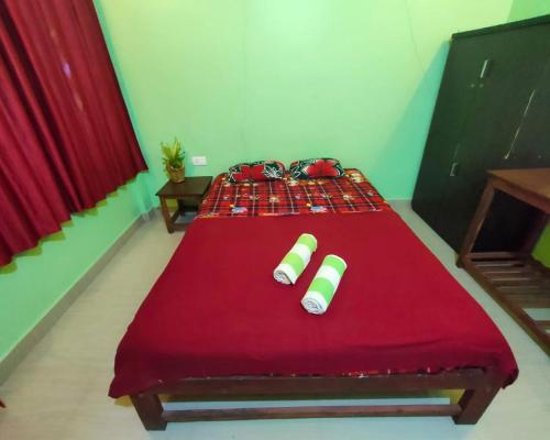 a bed with a red blanket and two cups on it at Luciano Guest House in Arambol