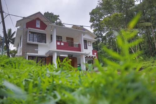a red and white house in the middle of the grass at God's gift in Devikolam