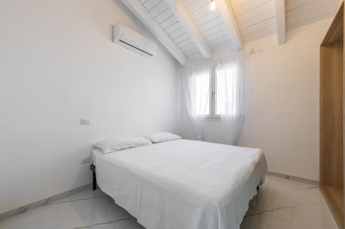a white bedroom with a bed in a room with a window at Casa Elena in Cagliari