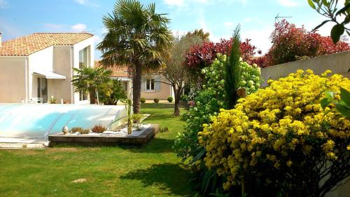 un jardin avec des fleurs jaunes et une clôture dans l'établissement Chambre d'Hôtes Armoise, à Lagord