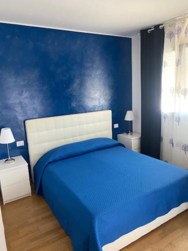 1 dormitorio azul con 1 cama con pared azul en Blue Sea Rooms Apartment Cagliari, en Cagliari