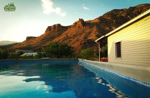 a swimming pool next to a building with a mountain at Eco Dom Tent in Yerevan