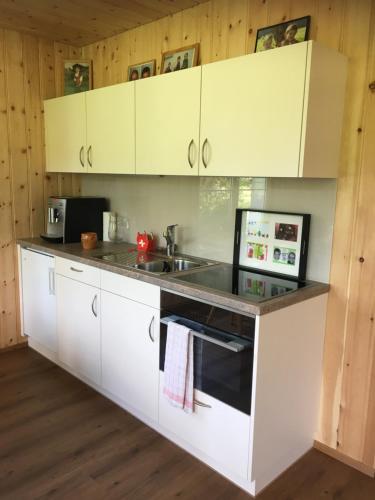 a kitchen with white cabinets and a sink at BnB-Blomberg in Ebnat