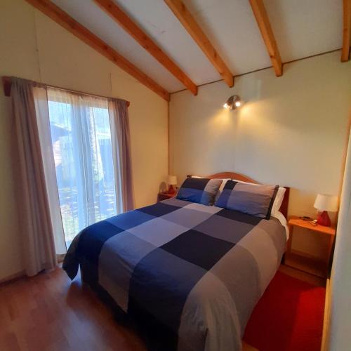 1 dormitorio con cama y ventana grande en Cabañas El Portal, en Neltume