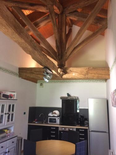 a kitchen with a wooden ceiling with wooden beams at La Grenouille in Saint-Adjutory