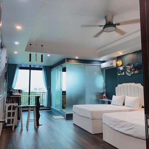 a bedroom with two beds and a desk and a balcony at Mio Hotel in Hải Dương
