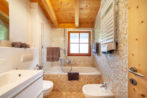 a bathroom with a tub and a toilet and a sink at Bergchalet Refugium Martius in Marlengo