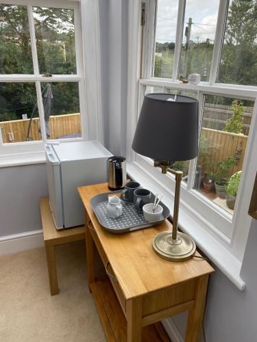 uma secretária com um candeeiro sobre uma mesa num quarto com janelas em Devonshire Terrace B&B em Truro