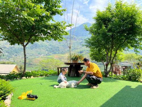 a man and a child playing with a dog on the grass at Sapa Eco Hugo in Sa Pa