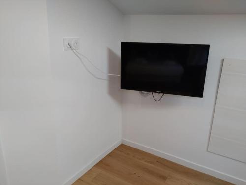 Elle comprend une télévision à écran plat suspendue sur un mur blanc. dans l'établissement studio cocoon BORDEAUX Chartrons/ Jardin Public, à Bordeaux