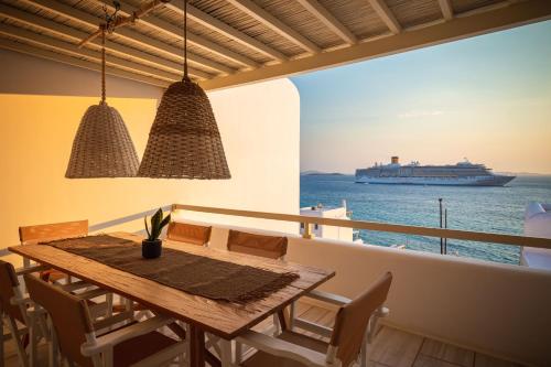 NAMASTE Boutique Apartments Mykonos في تورلوس: غرفة طعام مع سفينة سياحية في الماء