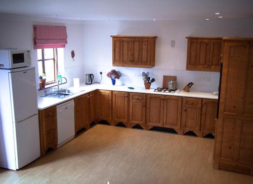 a kitchen with wooden cabinets and a white refrigerator at Beaufort House in Beaufort