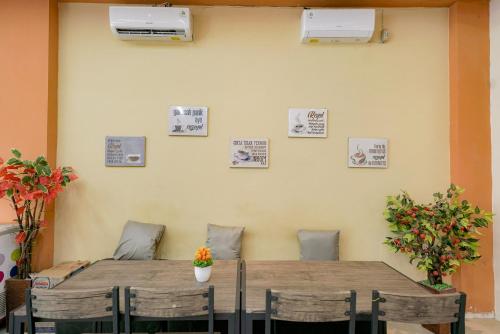 a table and chairs with pictures on the wall at Urbanview Hotel Gatot Subroto Lampung by RedDoorz in Geruntang
