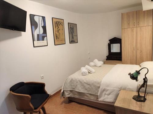 a bedroom with a bed and a chair and a television at RITSA ART RESIDENCE in Chania Town