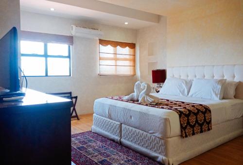 1 dormitorio con 1 cama blanca grande y TV en RedDoorz @ Joyce Palace Antique en San Jose de Buenavista