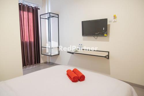 due pantofole rosse sedute su un letto con una TV di Astana Malioboro Mitra RedDoorz a Yogyakarta