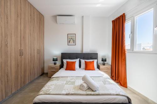a bedroom with a large bed with orange pillows at Olive 2-Bedroom Apartment in Larnaca in Larnaka