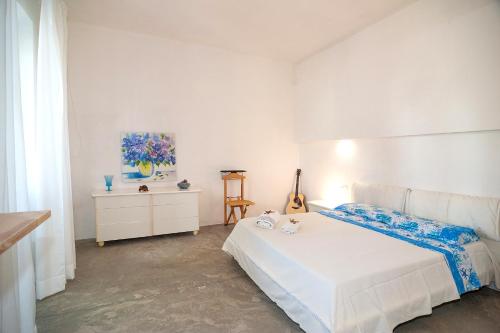 a white bedroom with a white bed and a dresser at CASA DELEDDA in Budoni