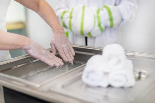 a person wearing gloves is washing their hands on a sink at Spa Hotel Diana in Františkovy Lázně