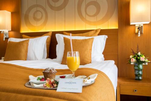 a bed with a tray of food and a glass of orange juice at Landmark Creek Hotel Plovdiv in Plovdiv