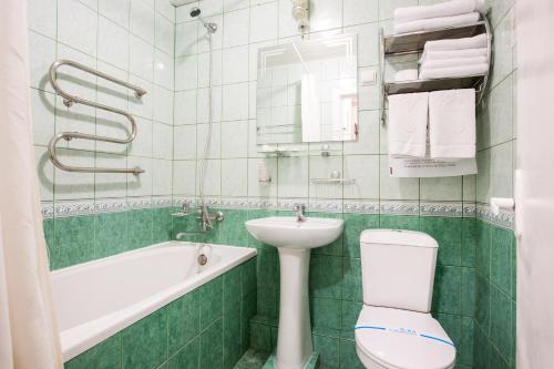 a bathroom with a toilet and a sink and a bath tub at Bukovyna Hotel in Chernivtsi