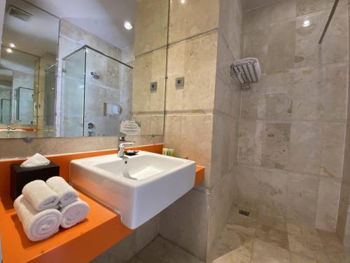 a bathroom with a white sink and a shower at Swiss-Belcourt Makassar in Makassar