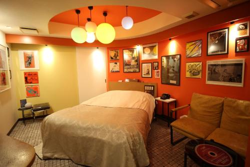a bedroom with orange walls and a bed and a couch at Hotel OLDSWING Adult Only in Tokyo