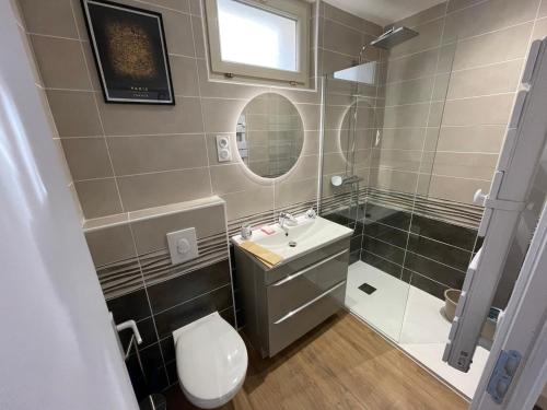 une salle de bain avec un lavabo, des toilettes et un miroir dans l'établissement 2- Quartier historique aux pieds des falaises, au Tréport