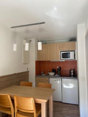 une cuisine avec une table en bois et un micro-ondes dans l'établissement Appartement charmant à La Tania, Courchevel, à Courchevel