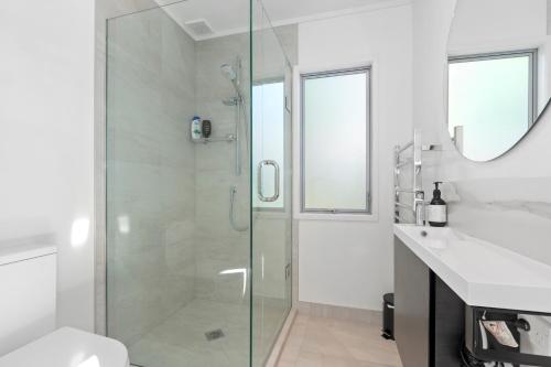 a bathroom with a glass shower and a sink at Beachy on Bream - Ruakākā Holiday Home in Ruakaka