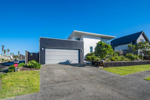 a house with a garage and a driveway at Beachy on Bream - Ruakākā Holiday Home in Ruakaka