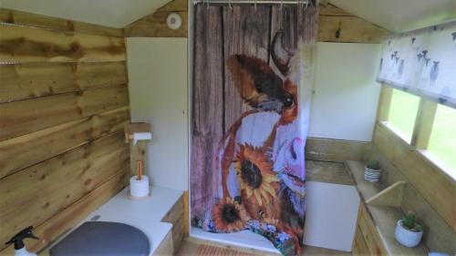 a bathroom with a shower with a painting on the wall at Ffos Wilkin Glamping & Alpacas in Kidwelly