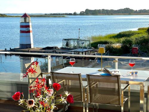 a table with wine glasses and a lighthouse on a dock at Apt "Sunset Lounge" in Waase - Ummanz - Meerblick, Kamin, Sauna in Mursewiek