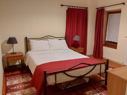 a bedroom with a large bed with red curtains at Traditional Guesthouse Vrigiis in Agios Germanos