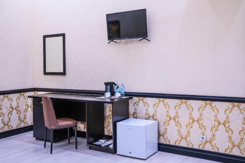 a room with a desk and a tv on a wall at Belon Lux Hotel in Astana