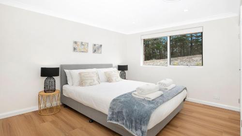 a white bedroom with a bed and a window at Sutton Forest Retreat The Hideaway in Sutton Forest