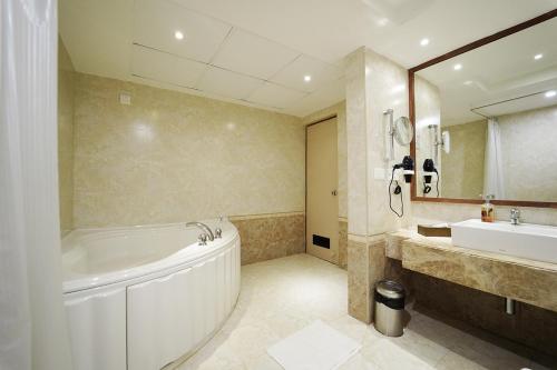 een badkamer met een groot bad, een wastafel en een bad bij Quality Inn VIHA in Kumbakonam