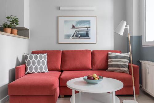 czerwona kanapa w salonie z białym stołem w obiekcie Sanhaus Apartments - PLAYA 2 - Apartament przy samej plaży w mieście Sopot