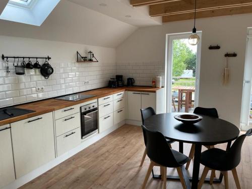 a kitchen with a black table and chairs and a table at Klein Westerland OG in Brodersby