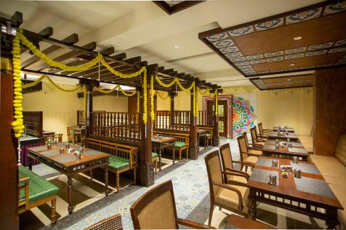 a dining room with wooden tables and chairs at Quality Inn VIHA in Kumbakonam
