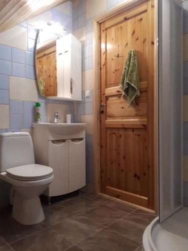een badkamer met een toilet en een houten deur bij Brīvdienu Māja Brenguļos in Myza Brenguli