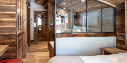 a bedroom with wood walls and a large window at Hotel le Petit Dru in Morzine