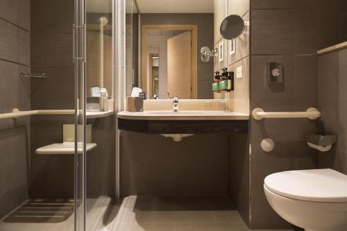 a bathroom with a sink and a toilet and a mirror at voco Venice Mestre - The Quid by IHG in Mestre