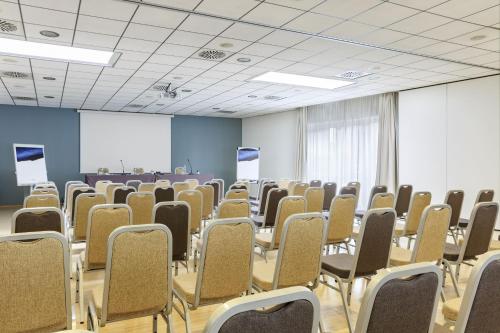 an empty room with chairs and a projection screen at voco Venice Mestre - The Quid by IHG in Mestre