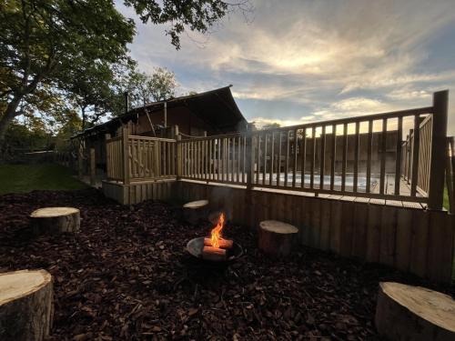 a fire pit in a yard next to a fence at Robin Hood Safari Tent in Tenby