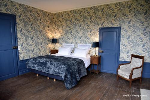 a bedroom with a bed with blue walls and a chair at Domaine de la Briouse in Sanxay