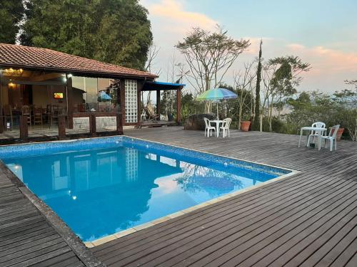 a swimming pool with a deck and a house at Recanto Cravo e Canela in Itatiaia