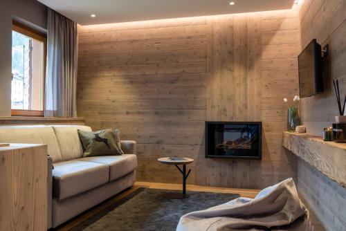 a living room with a couch and a tv at Suite Mia in Falcade