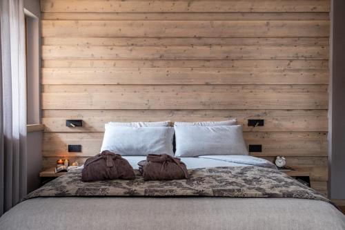 1 dormitorio con 1 cama grande y pared de madera en Suite Mia en Falcade